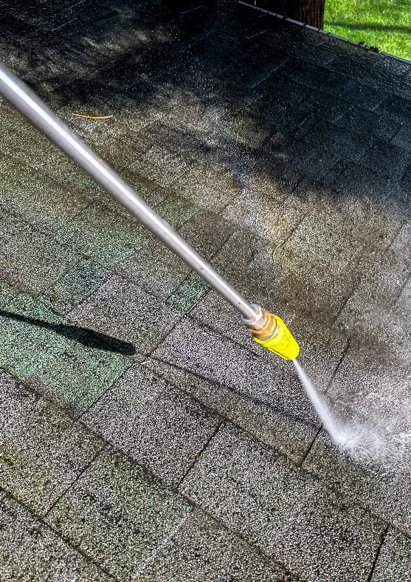 tsunami pressure washing cleaning an asphalt roof in chelseaal Pressure washing technician cleaning an asphalt shingle roof in Hoover, Alabama to remove dirt, algae, and stains.
