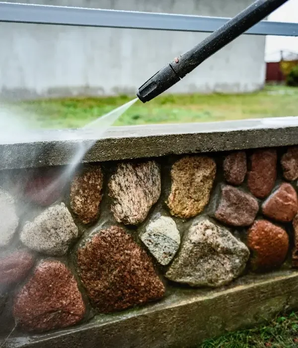 pressure washing rock wall in chelsea al High-pressure water cleaning a stone retaining wall during a residential exterior wash in Hoover, Alabama.